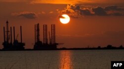 Нефтедобывающие конструкции на фоне заката солнца, штат Луизиана, США